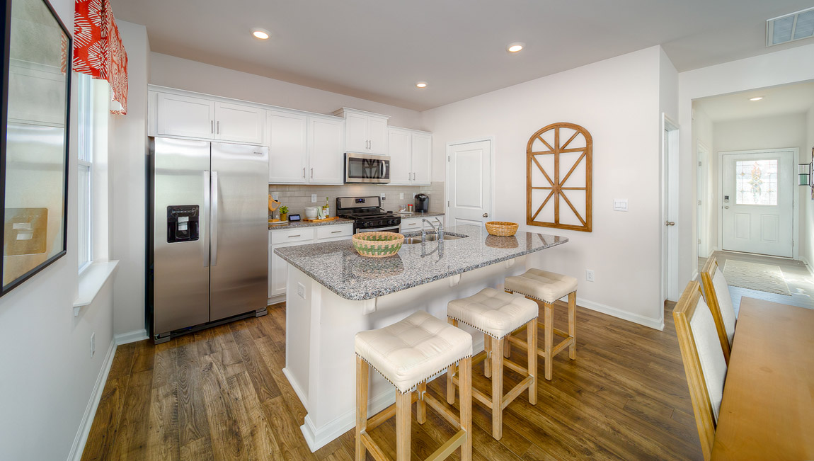 kitchen and island with white cabinets, wood floors and stainless steel appliances