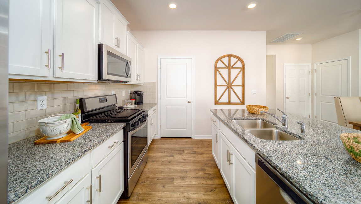 kitchen and island with white cabinets, wood floors and stainless steel appliances