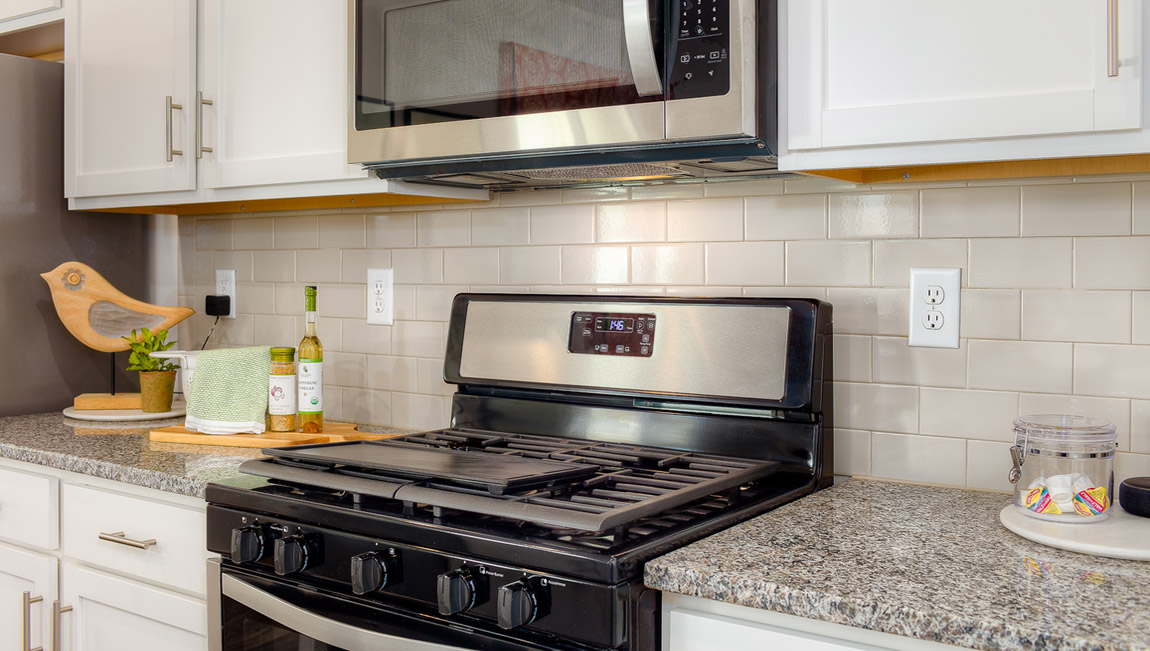 kitchen and island with white cabinets, wood floors and stainless steel appliances
