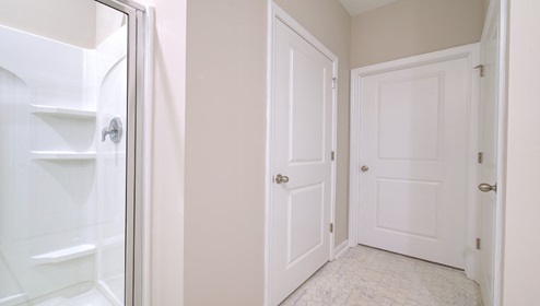 Primary bathroom with double sink vanity, white cabinets, and standing glass door shower