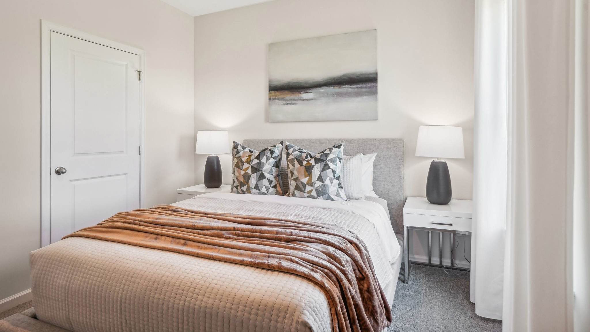 Model primary carpeted bedroom with large window