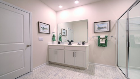 Bathroom with white cabinets and counters, and glass door shower