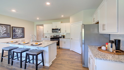 Kitchen and island wit white cabinets, granite counters, white subway tile backsplash, and stainless steel appliances