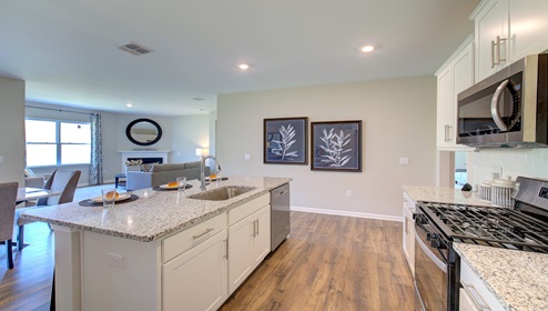 Kitchen and island wit white cabinets, granite counters, white subway tile backsplash, and stainless steel appliances