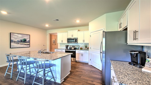 Kitchen and island with wood floors, white cabinets, and stainless steel appliances