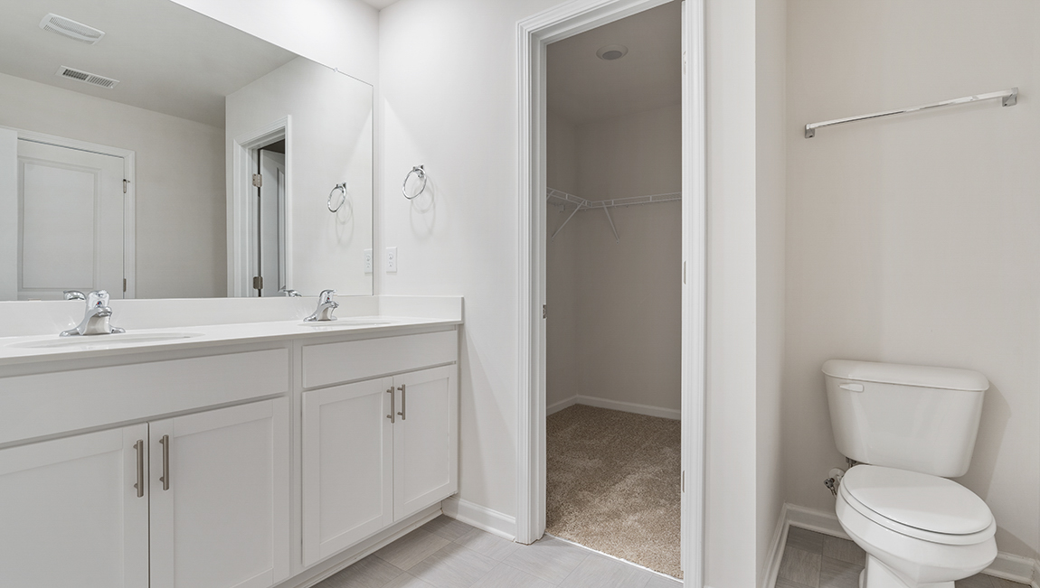Primary bathroom with white cabinets, counters, and glass door shower