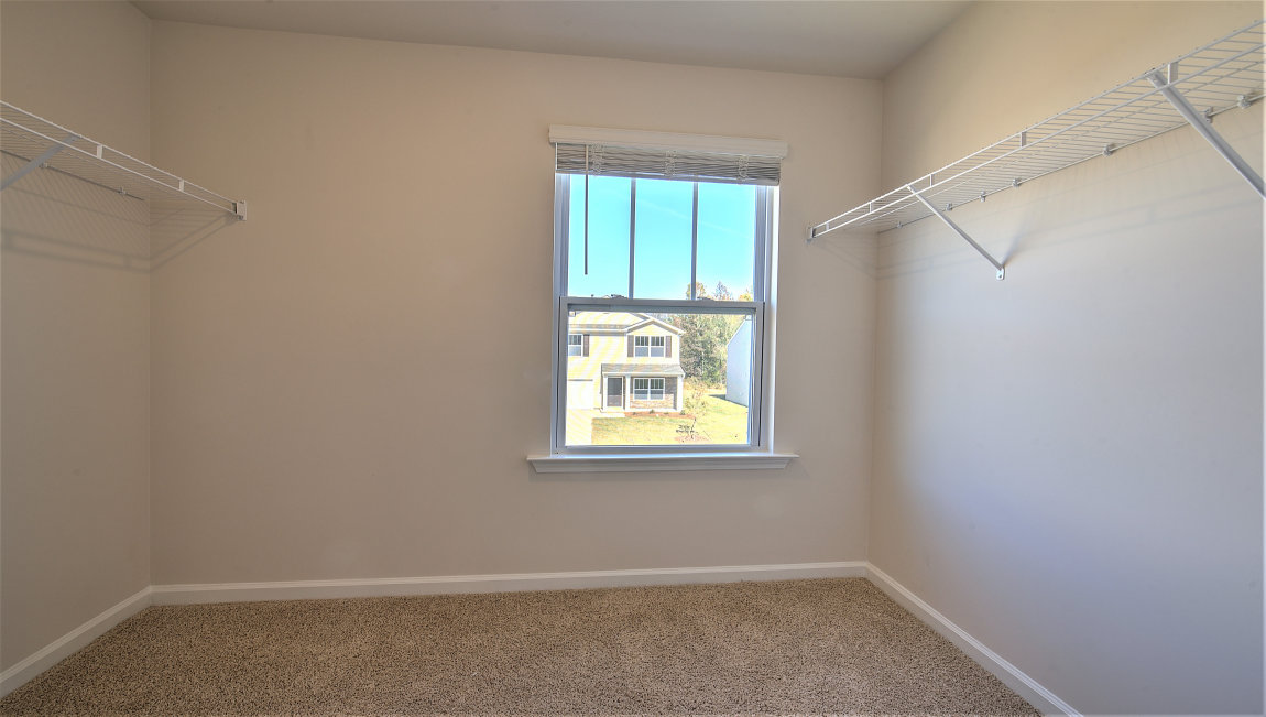 Primary bedroom walk in closet with small window