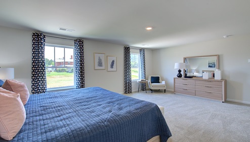 Primary bedroom with carpet, and two small windows