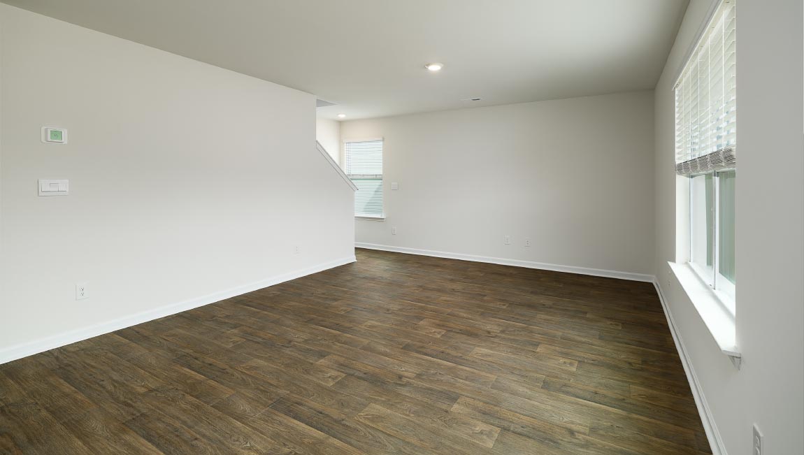 Open great room beside kitchen, against staircase, with large window