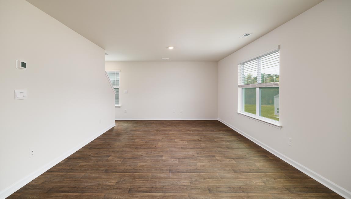 Open great room beside kitchen, against staircase, with large window