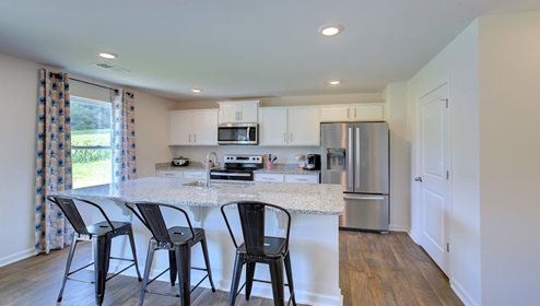 Kitchen and island with white cabinets, granite countertops, and stainless steel appliances