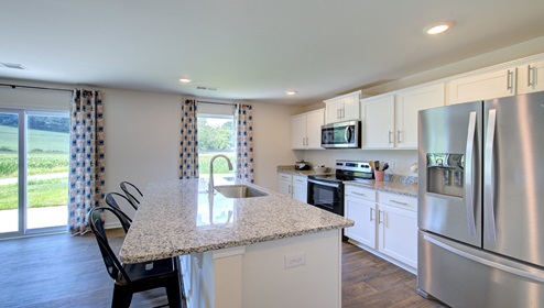 Kitchen and island with white cabinets, granite countertops, and stainless steel appliances