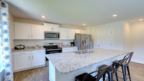 Kitchen and island with white cabinets, granite countertops, and stainless steel appliances