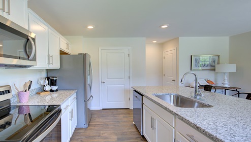Kitchen and island with white cabinets, granite countertops, and stainless steel appliances
