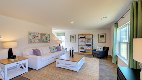 Great room with view of kitchen, has large windows and is against staircase