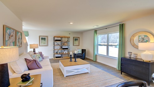 Great room with view of kitchen, has large windows and is against staircase