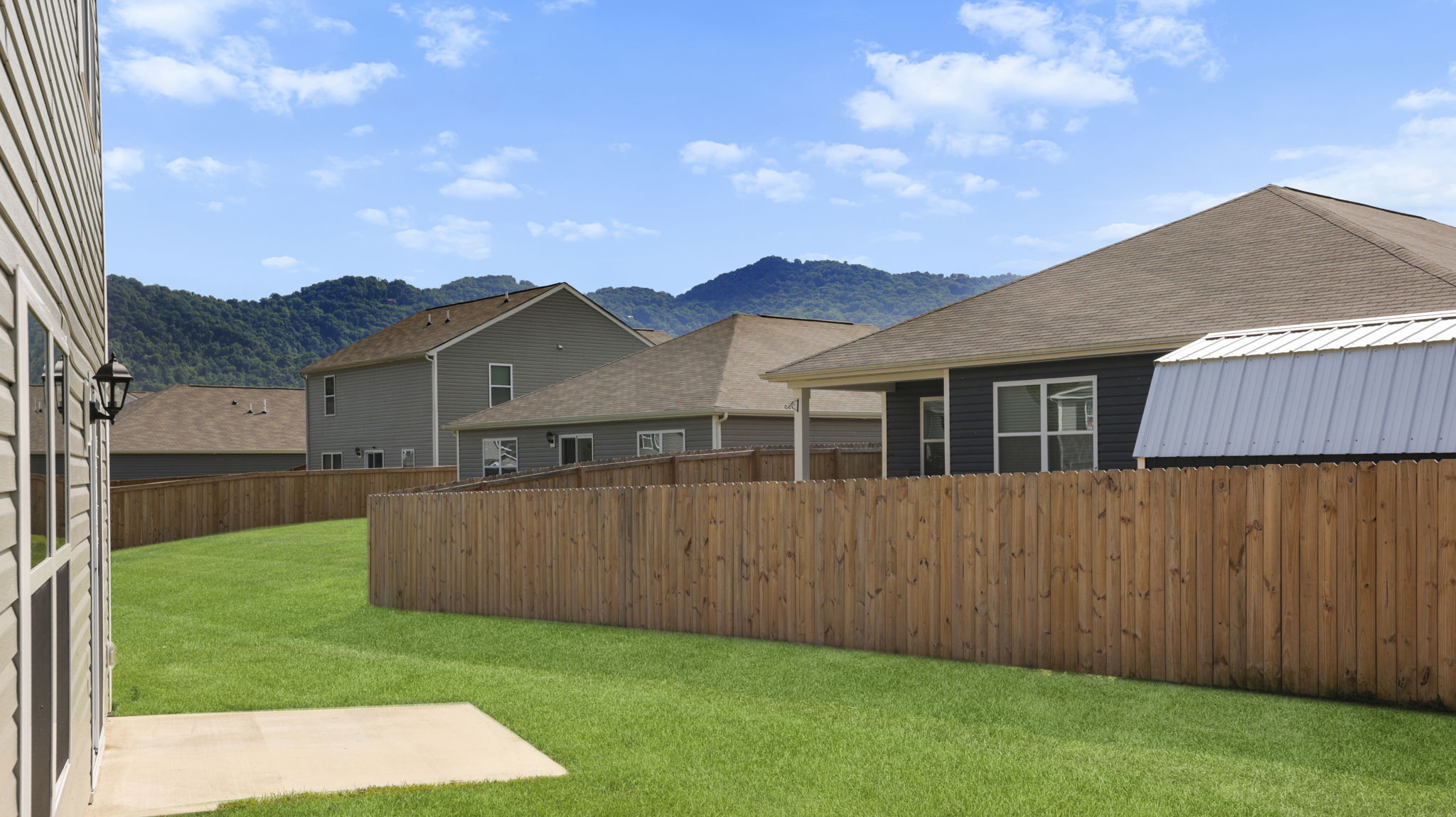 Backyard with privacy fence, green grass and blue sky