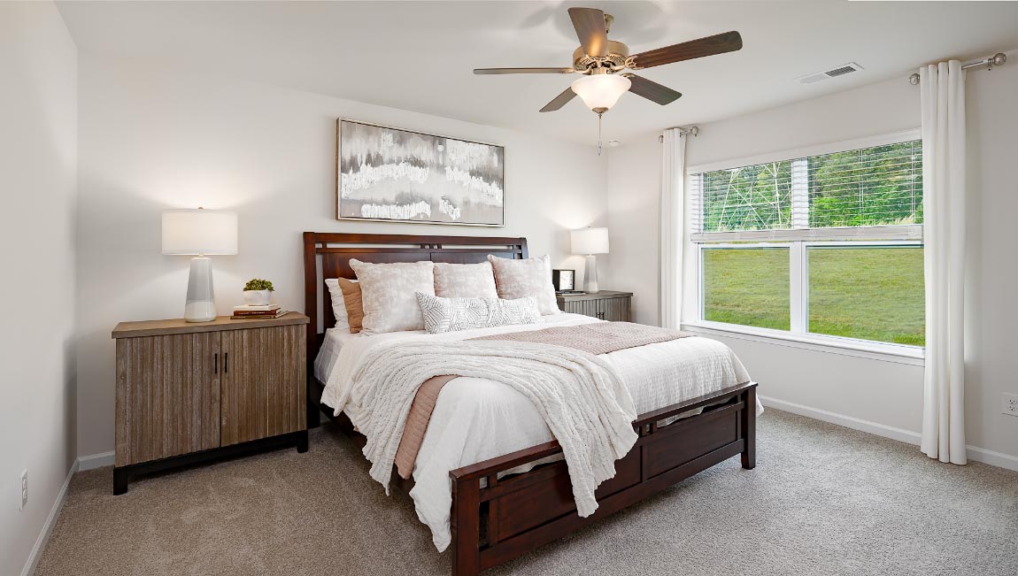 Carpeted primary bedroom with large windows
