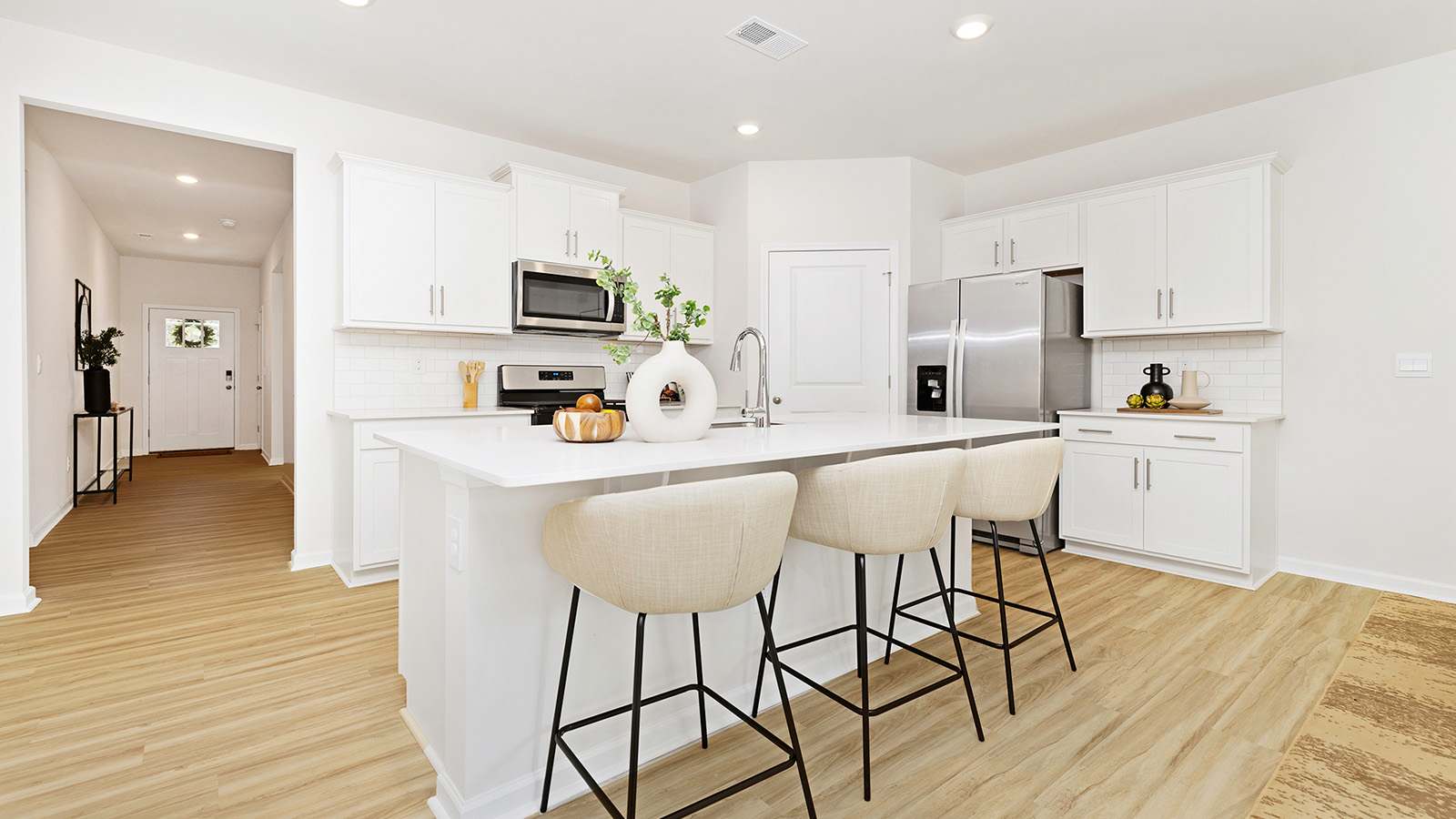 Kitchen and island with white cabinets and subway tiles and stainless steel subway tiles