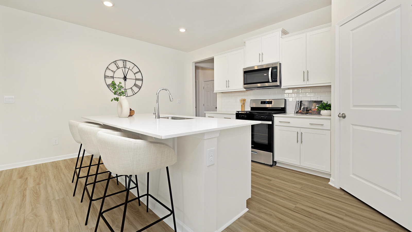 Kitchen and island with white cabinets and subway tiles and stainless steel subway tiles