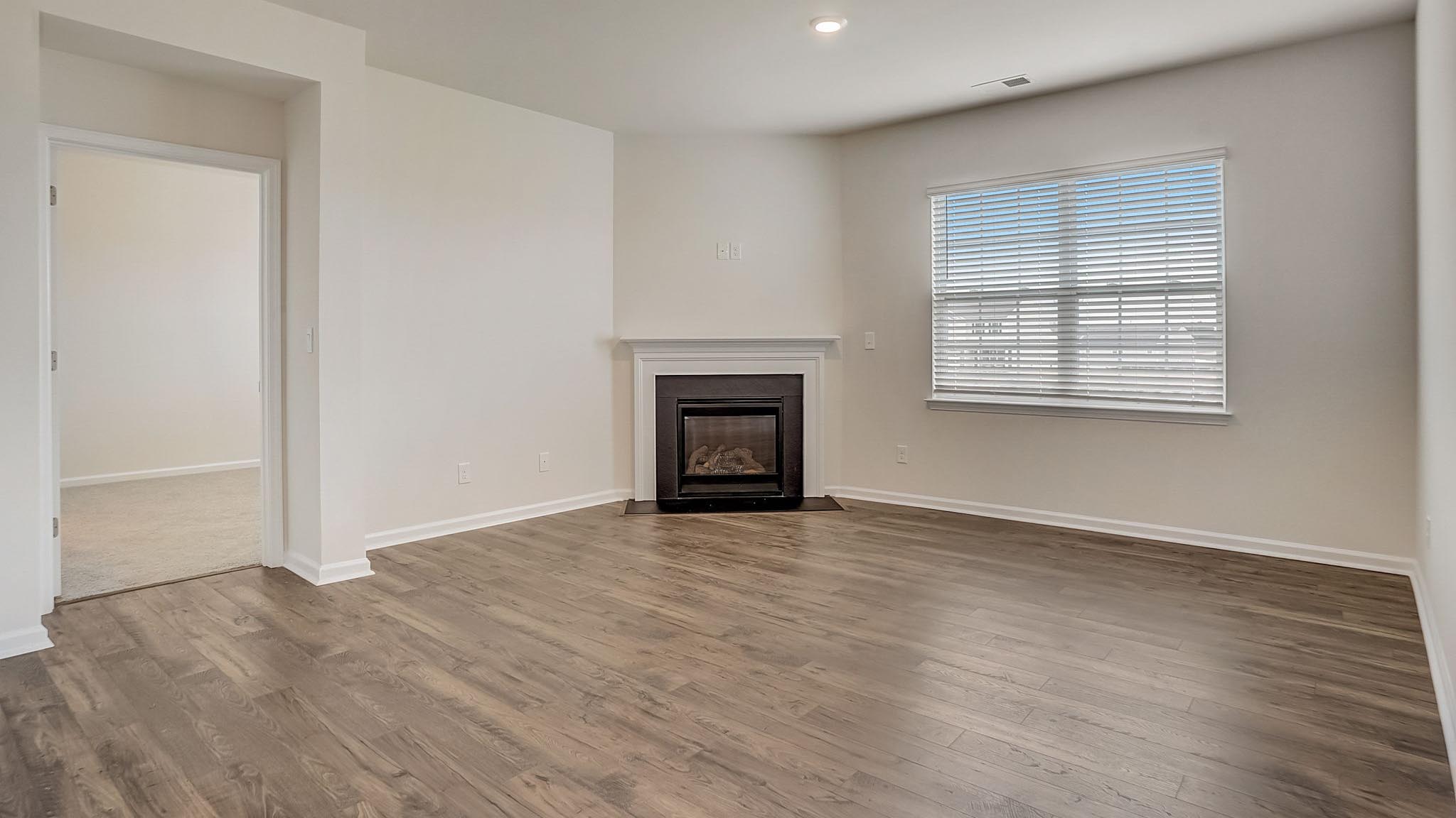 Open living room with wood floors, large window, and fireplace