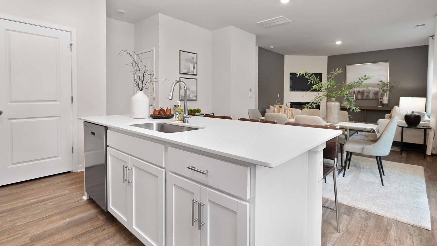 Kitchen and island with white cabinets and counters, vinyl floors and stainless steel appliances
