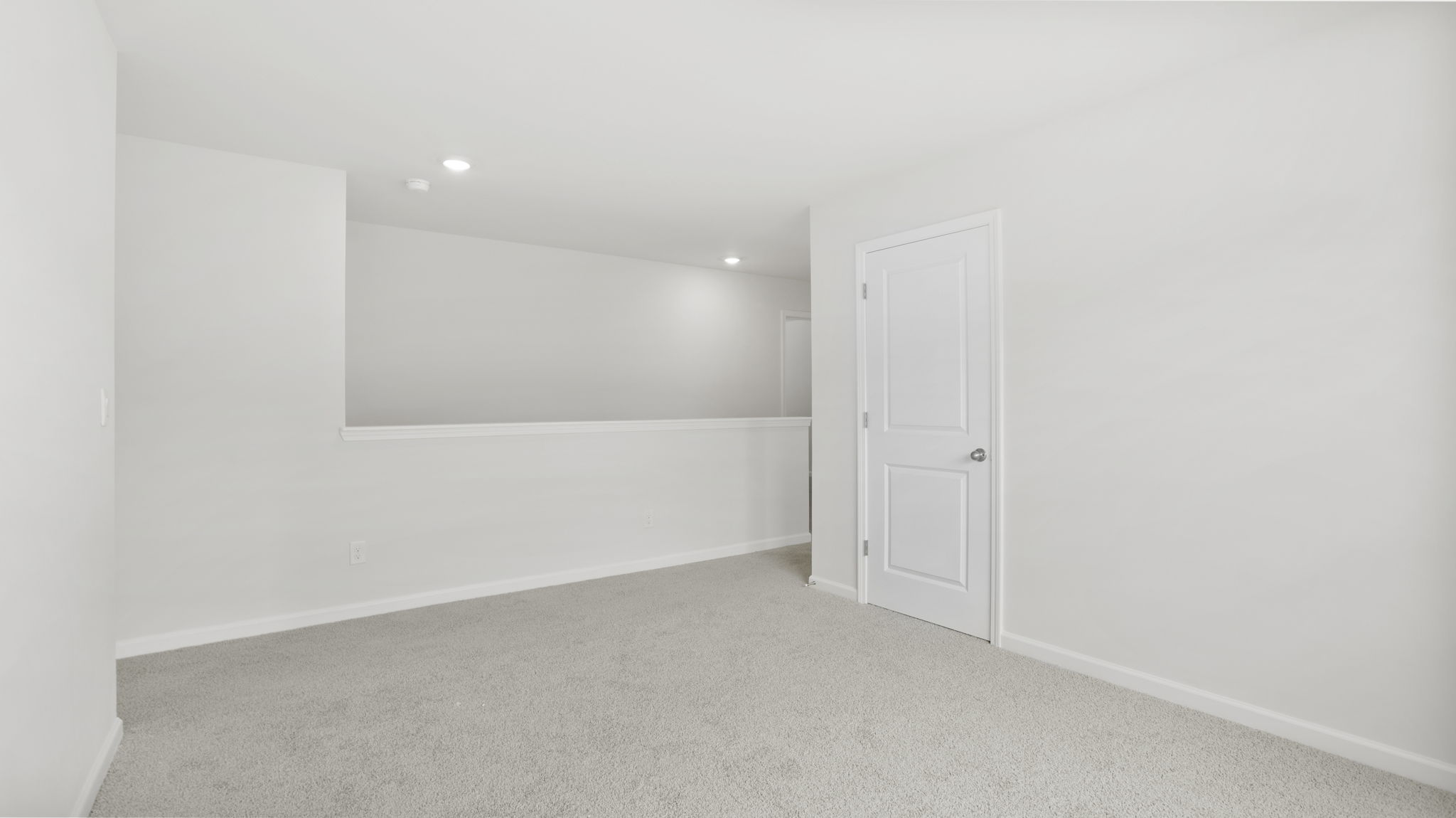 Carpeted loft area with view of stairs