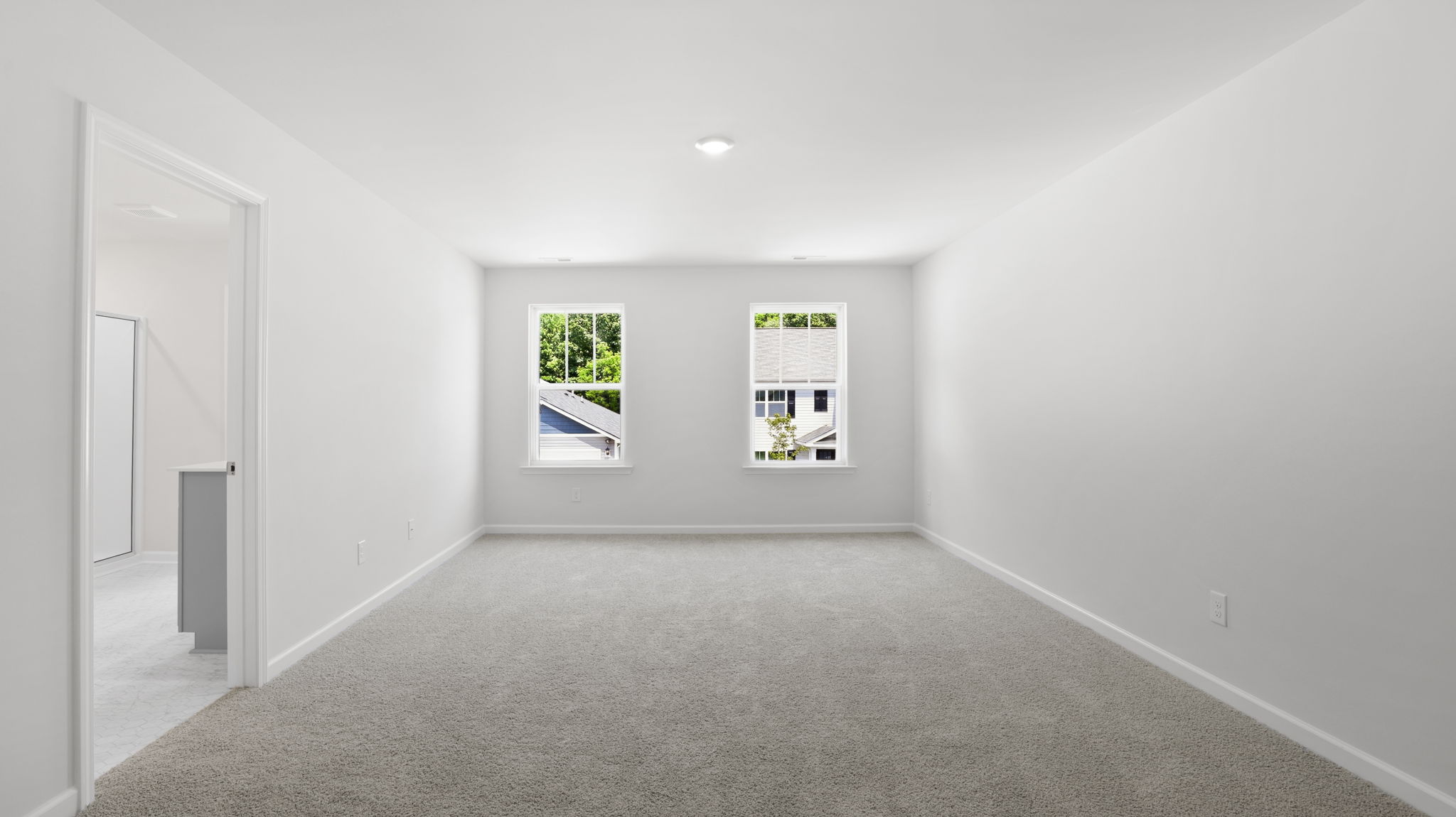 Carpeted primary bedroom with large windows