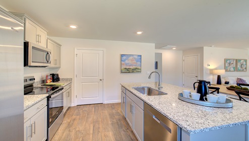 Kitchen and island with gray cabinets and stainless steel appliances