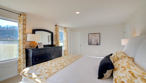 carpeted primary bedroom with two large windows