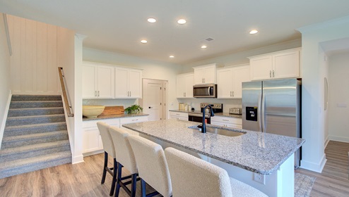 Kitchen and island with wood floors, white cabinets, and stainless steel appliances
