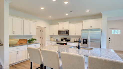 Kitchen and island with wood floors, white cabinets, and stainless steel appliances