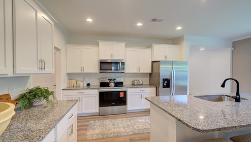 Kitchen and island with wood floors, white cabinets, and stainless steel appliances