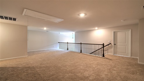 Upstairs loft space, carpeted, with staircase railing