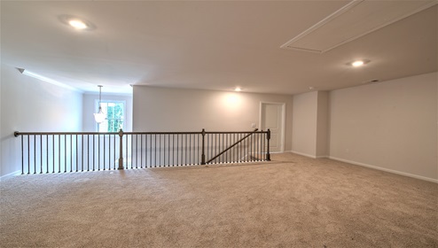 Upstairs loft space, carpeted, with staircase railing