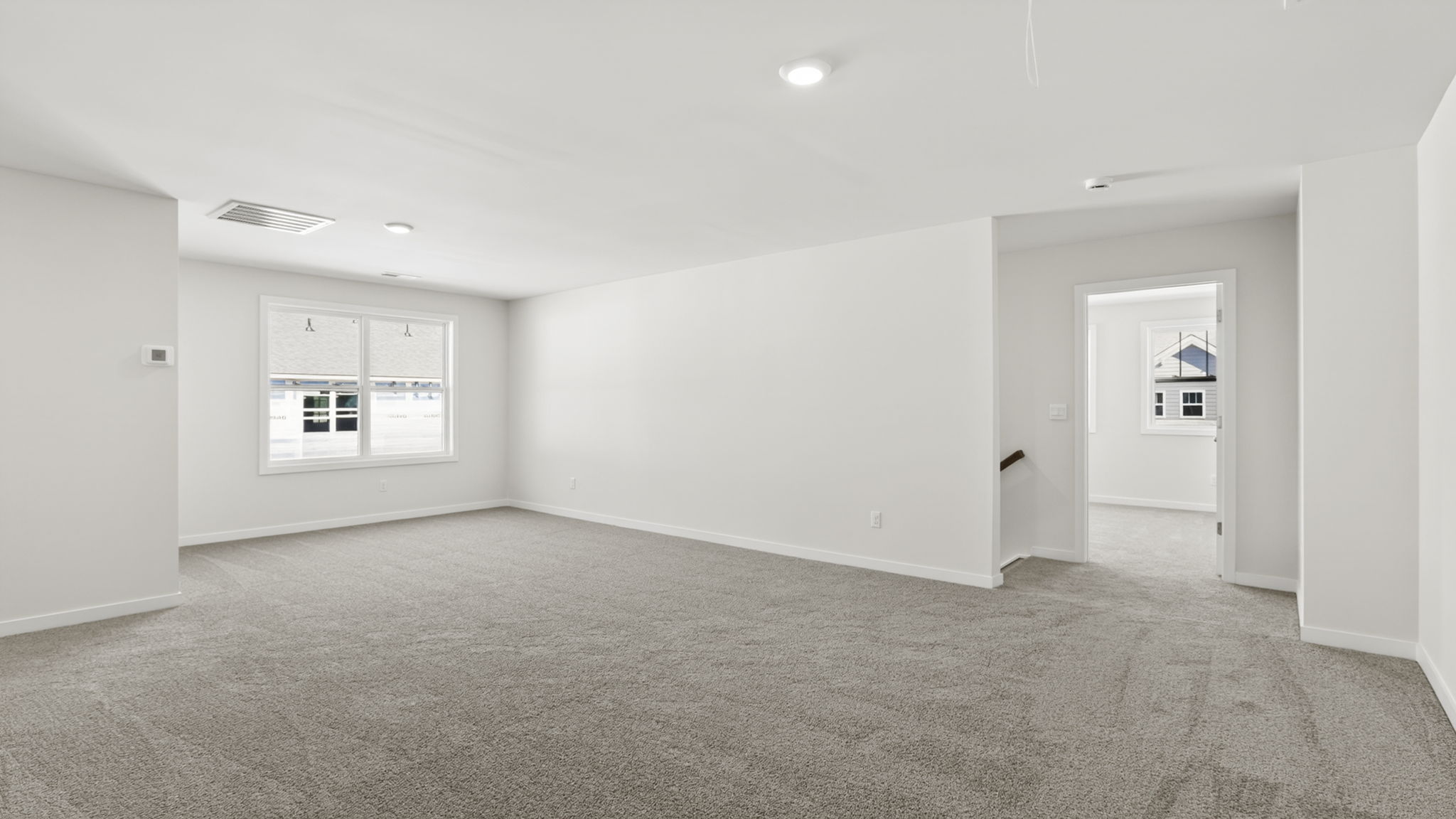 Carpeted loft area with large windows