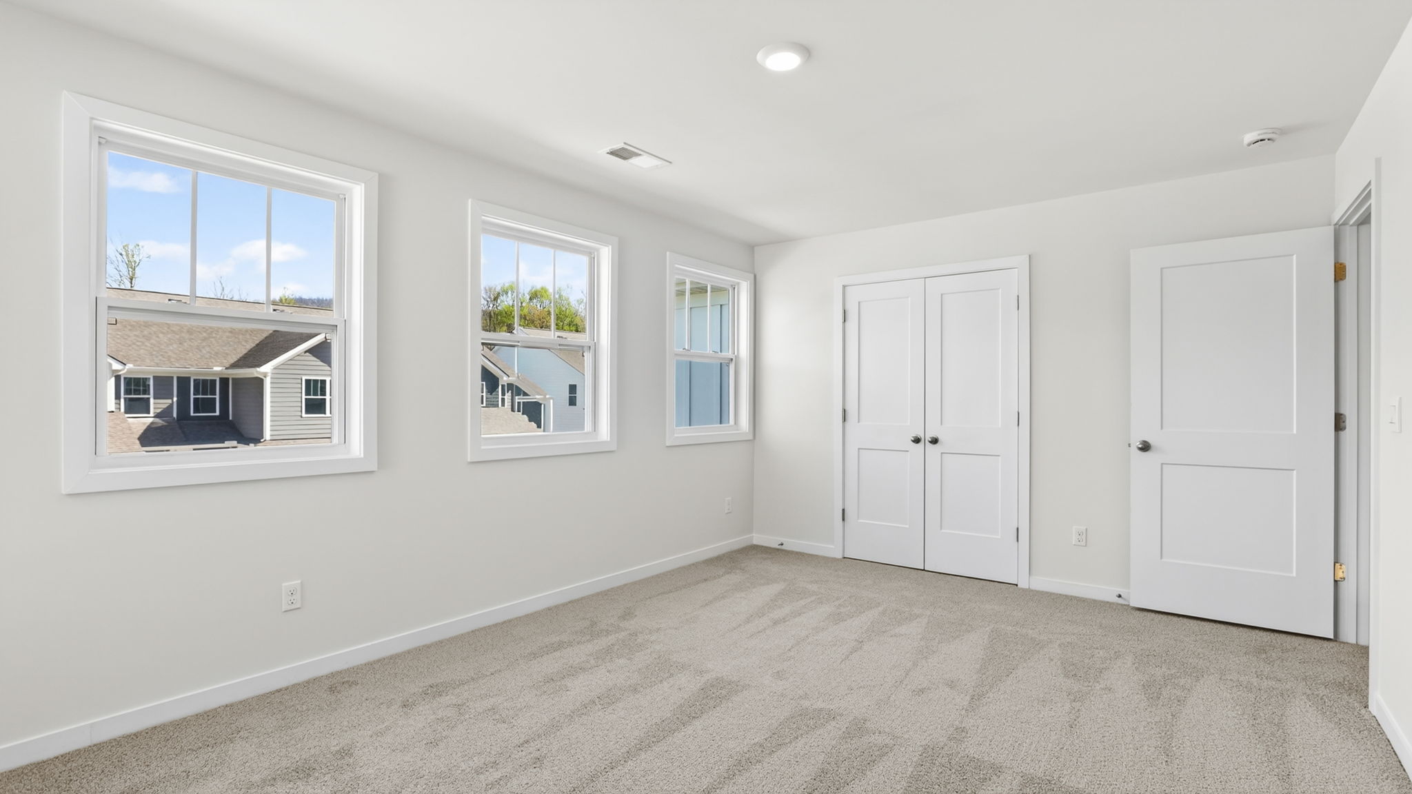 Carpeted front bedroom with large windows