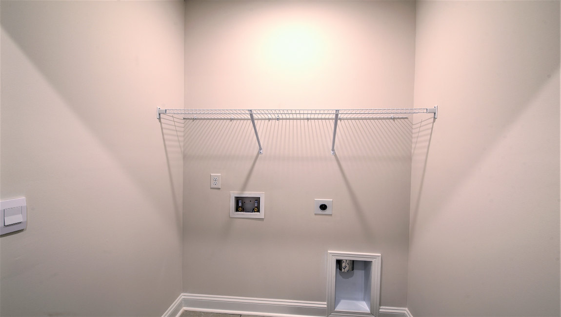 Laundry room with built in racks above machine space