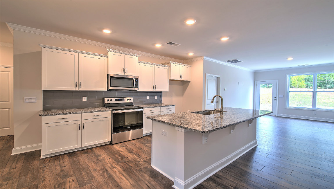 Kitchen and island with wood floors, white cabinets, and stainless steel appliances