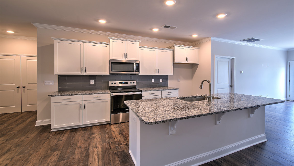 Kitchen and island with wood floors, white cabinets, and stainless steel appliances