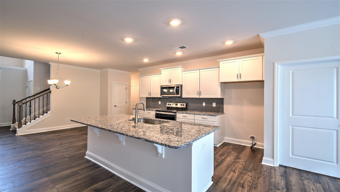 Kitchen and island with wood floors, white cabinets, and stainless steel appliances