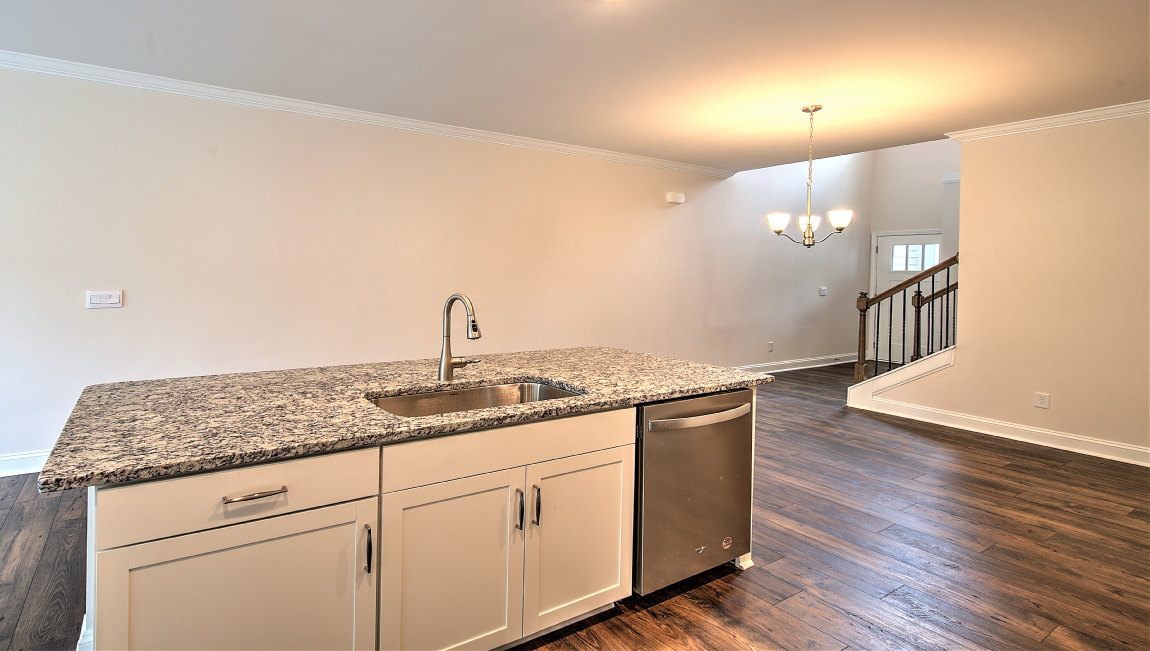 Kitchen and island with wood floors, white cabinets, and stainless steel appliances