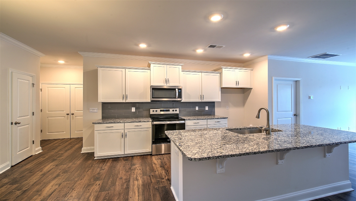 Kitchen and island with wood floors, white cabinets, and stainless steel appliances