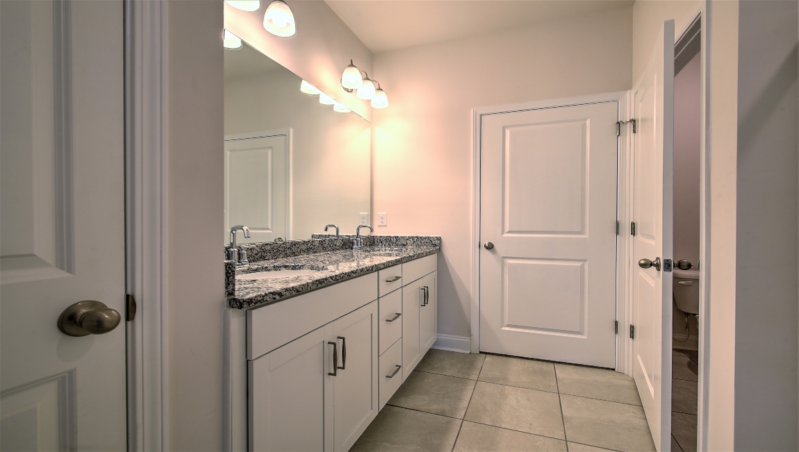 Bathroom with double sinks, and white cabinets