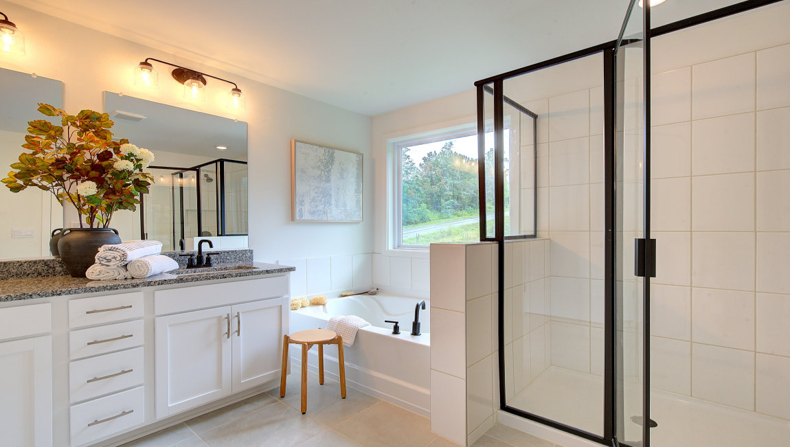 Primary bathroom with double vanity, bathtub and walk in shower