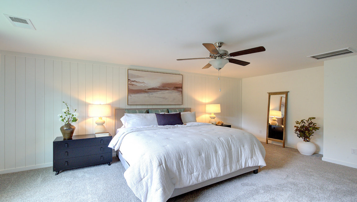 Carpeted primary bedroom with large windows