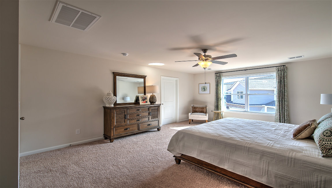 Primary bedroom with carpet, ceiling fan, and large window