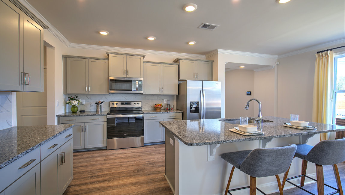 Kitchen and island with grey cabinets and stainless steel appliances