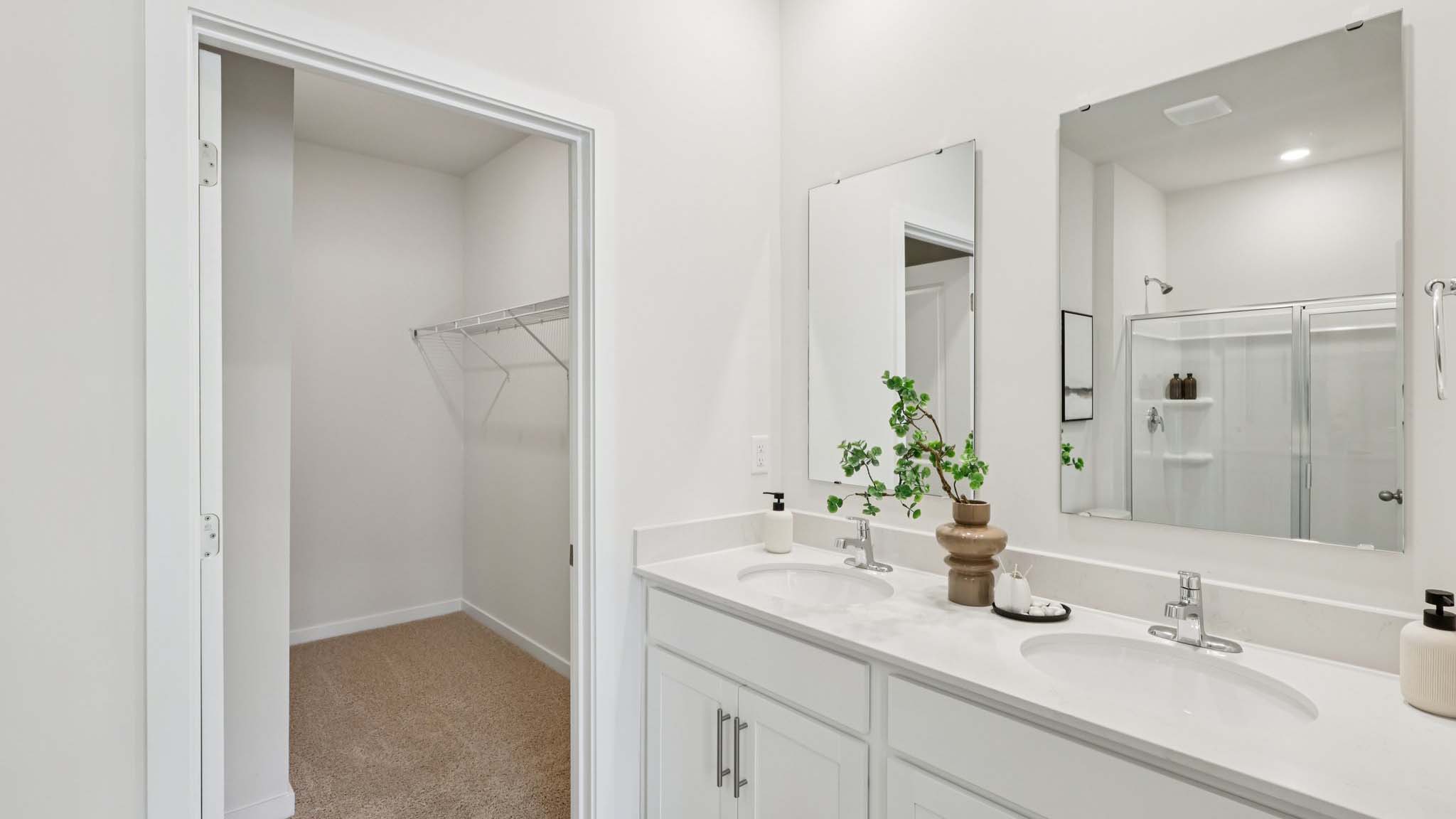 Primary bathroom with view of walk in closet and dual vanity