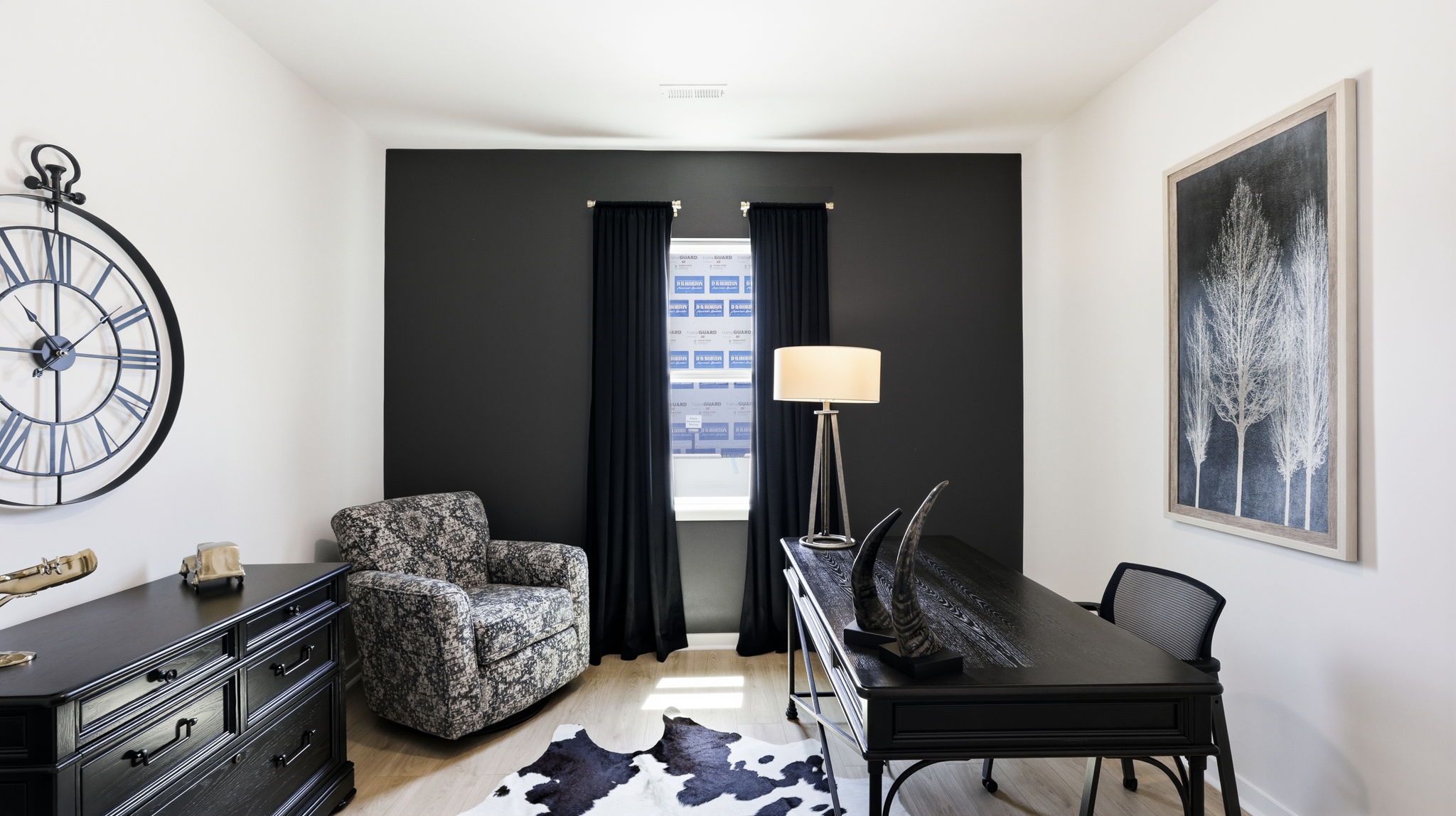 Carpeted bedroom set up as a home office with large window and black accent wall